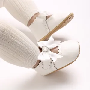 Detailansicht von niedlichen weißen Baby-Prinzessinnenschuhen mit Schleife und Herz-Strass