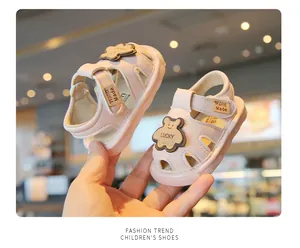 Soft sole pink toddler sandals featuring a cute cartoon bear decoration held by hand
