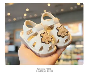 Close-up of off-white baby sandals with cute bear patch and closed-toe design