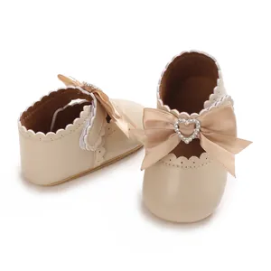 Elegante beige Baby-Prinzessin-Schuhe mit dekorativer Herz-Strass-Schleife im Detail.