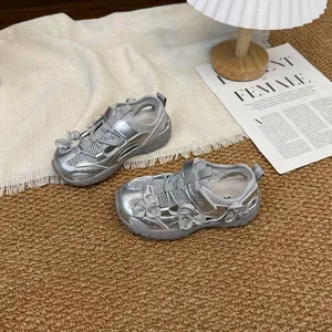 Vista detallada de zapatillas de malla plateadas para niña con flores sobre una alfombra