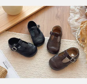 Detailed close-up view of children's T-strap brogue shoes in black and brown premium leather