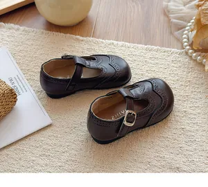 Detail of girls' brown leather T-strap Mary Janes with elegant brogue patterns