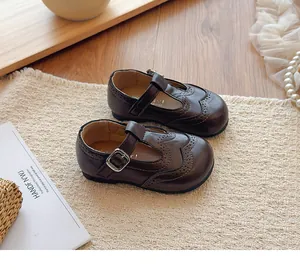 Detail view of dark brown leather Mary Jane shoes for girls with brogue patterns