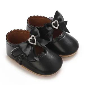 Detailansicht von Baby-Mädchen-Prinzessinnenschuhen mit Satinschleife und Herz-Strass