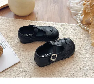 Close-up of black leather Mary Jane shoes for girls featuring elegant brogue patterns