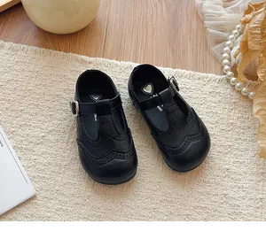 Close-up of black T-strap Mary Jane shoes for girls with brogue perforated details.