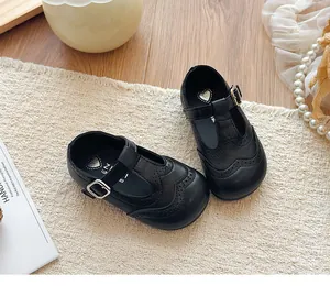 Detailed view of black T-strap girls' leather shoes with elegant brogue patterns