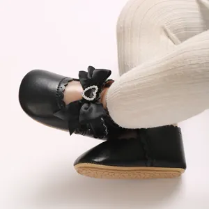 Detail von schwarzen Baby-Prinzessinnenschuhen mit Schleife und glitzernder Herzschnalle