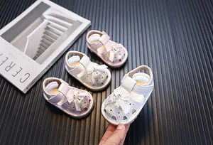 Sandalias cerradas para niñas con lazo y perlas, presentadas sobre fondo oscuro.