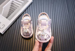Primer plano de sandalias rosas para bebé niña con lazo de perlas y recortes de corazón