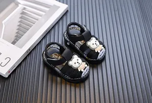 Detailed view of black cartoon bear baby sandals with soft soles and closed toes.