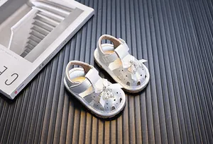 Vista detallada de sandalias blancas para bebés con lazo decorativo y perlas elegantes