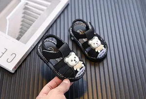 Close-up view of black baby boy closed-toe sandals with a cute white cartoon bear decoration