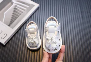 Detalle de sandalias blancas para niñas pequeñas con lazo de perlas