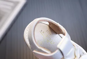 Primer plano de sandalias blancas para bebés con plantilla dorada y cuero suave