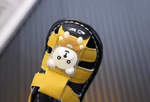 Detailed close-up showing the cute cartoon bear decoration on yellow baby boy sandals