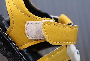 Macro view of yellow toddler sandal featuring a secure hook-and-loop Velcro strap detail