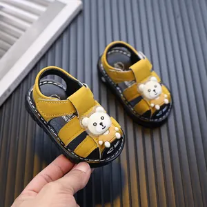 Yellow closed-toe baby sandals with a cartoon bear design and soft toddler soles