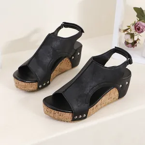 Dettaglio di sandali neri con zeppa, suola in sughero platform e decorazioni con rivetti