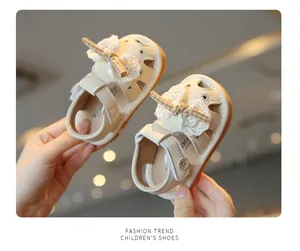Detailed view showing cream baby sandals with elegant lace bows and heart hollow-out design.