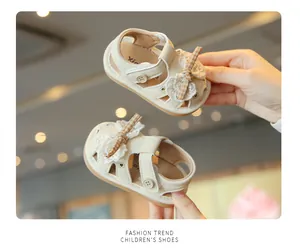 Close-up of cream-colored baby sandals featuring lace bows and breathable soft soles