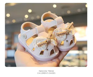 Detailed macro view of pink baby princess sandals with lace flower and checkered bow