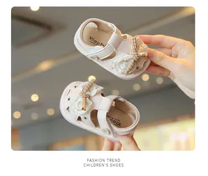 Close-up of pink baby summer sandals with lace bows and hollow breathable design