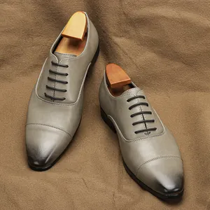 Classic men's grey leather Oxford dress shoes with burnished cap toe on fabric