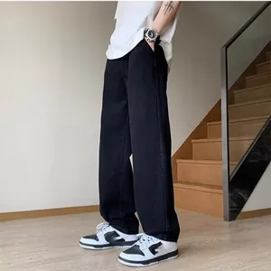 Detailed view of men's loose straight-leg black jeans with a high-street baggy aesthetic