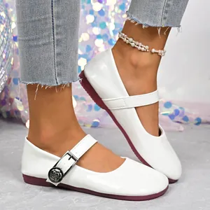 Detailed view of white retro Mary Jane flats with rose buckle and burgundy sole.