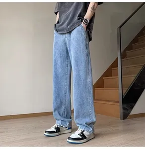 A full-length view of men's loose straight-leg denim jeans in light blue wash for street style