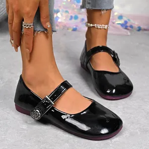 Close-up of black patent leather Mary Jane flats with rose buckle detail