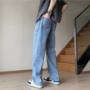 Side view of men's loose straight leg light wash blue jeans in a modern indoor setting