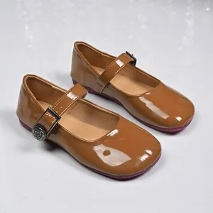 Close-up detail of glossy brown patent leather Mary Janes featuring decorative rose buckle