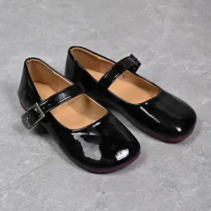 Detail view of black patent leather Mary Jane flats with decorative camellia buckle