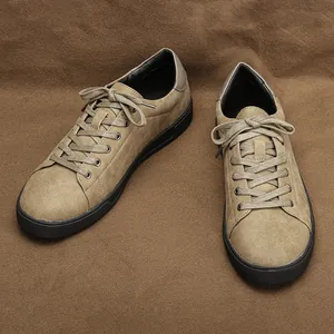 Vista detallada de zapatillas de gamuza caqui para hombre sobre un fondo marrón.