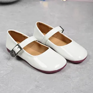 Close-up of elegant white patent leather Mary Jane flats with decorative rose buckle
