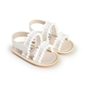 Detailed view of white baby walking sandals with cute pom-pom trim and soft sole