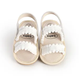 Detailed top view of cream baby walking shoes featuring soft white pom-pom straps