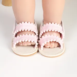 Detailed close-up of pink infant girl summer sandals with decorative soft pom-pom trim