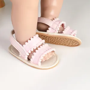 Detailed view of pink baby walking sandals featuring cute pom-pom edges and soft anti-slip soles