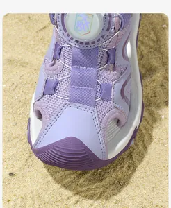 Macro detail of purple closed-toe children's sport sandal with mesh upper on beach sand
