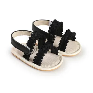 Close-up of black baby walker sandals featuring white insoles and cute pom-pom trim.