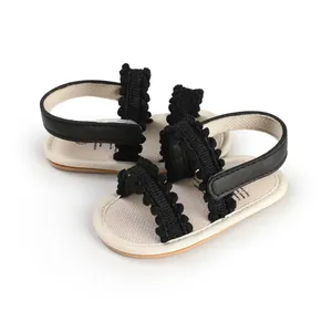 Detail view of breathable black knit baby sandals with pom-pom accents for infants
