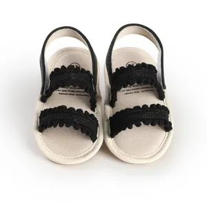 Detailed view of baby walker sandals with black pompom fringe and elastic back strap