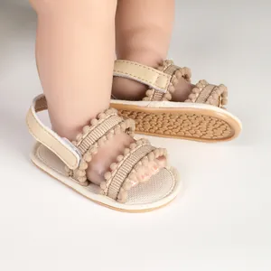 Close-up view of beige baby sandals with decorative straps and non-slip sole detail