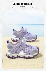 Detailed macro view of purple kids' sports beach sandals with rotating dial closure on sand.