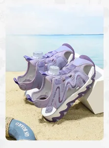 Close-up of purple kids sports sandals with closed-toe design on a sunny sandy beach