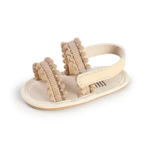 Beige soft sole baby walking sandals with cute pom-pom trim and adjustable strap